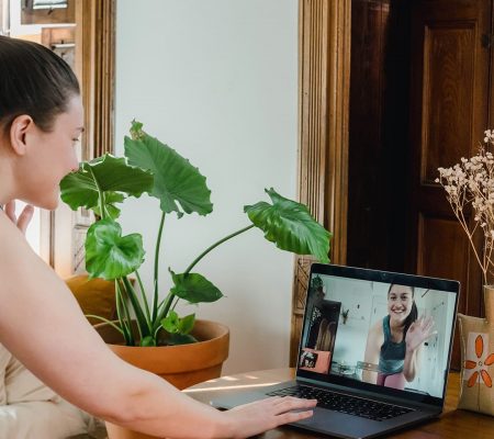 Woman smiles at her teacher on a laptop screen before an online fitness class