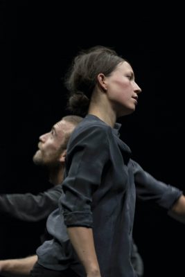 Company Tumbleweed (Angela Rabaglio, Micaël Florentz) Woman and man in dark green against dark background. Woman, in front, faces left. The man, behind and below, faces right. The Gyre. Photo: Flurin Bertschinger