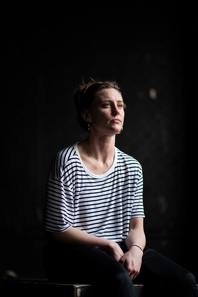 Woman in breton t-shirt, seated against dark background